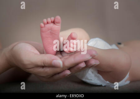 Neonato ragazzo in piedi cullata in madri di mano Foto Stock