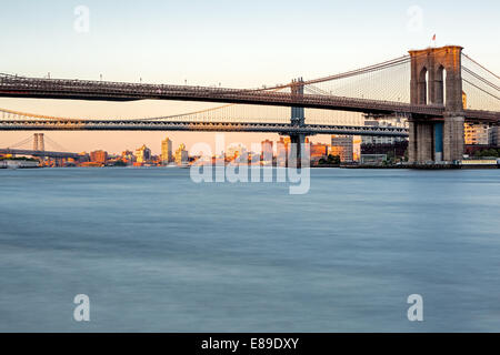 Brooklyn, Manhattan e Williamsburg ponti durante l ora d'oro al tramonto. Come si vede da South Street Seaport in Lower Manhattan a New York City. Foto Stock