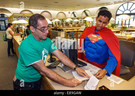 Miami Florida,Miami-Dade Public Library,informazioni,desk,help,bibliotecario,aiutare,indossare,Superman,costume,uomo ispanico maschio,FL140420086 Foto Stock