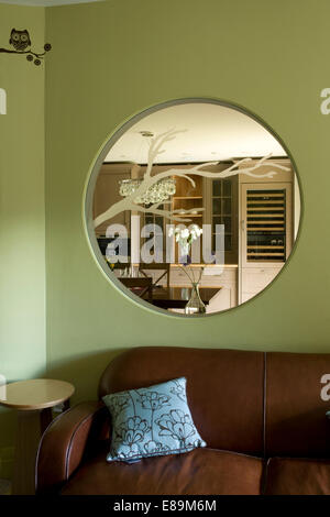 Interno in vetro inciso oblò finestra sopra divani in pelle marrone verde in salotto Foto Stock