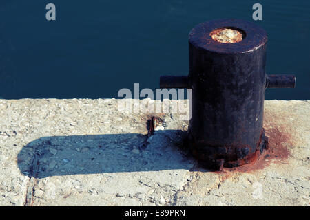 Vecchio arrugginito bollard ormeggio sulla costa del mare, effetto tonico Foto Stock