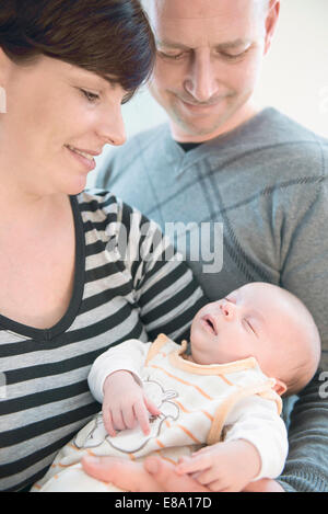 I genitori tenendo il loro bambino nelle braccia, sorridente Foto Stock
