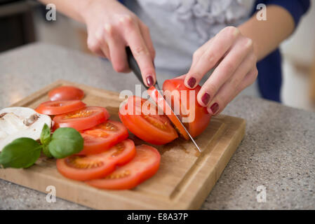 Ragazza adolescente il taglio di pomodori, close up Foto Stock