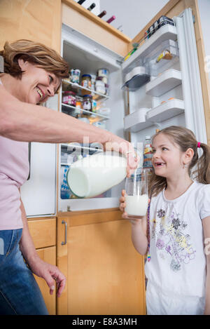 Nonna versando il latte in vetro per la nipote Foto Stock