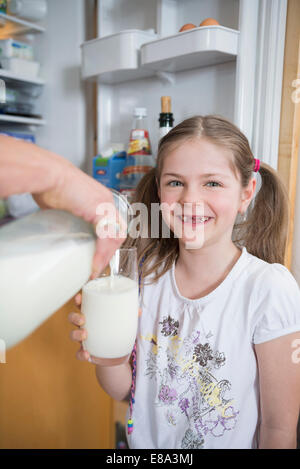 Nonna versando il latte in vetro per la nipote Foto Stock