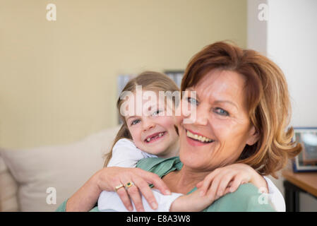 Ritratto di Nonna e nipote seduta sul divano nel soggiorno, sorridente Foto Stock