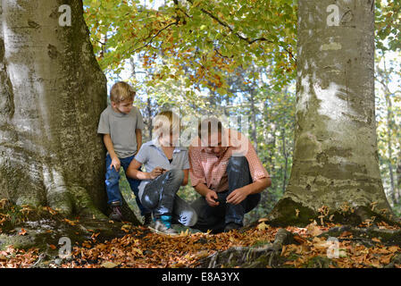 Padre mostrando qualcosa per i suoi figli in foresta, Baviera, Germania Foto Stock