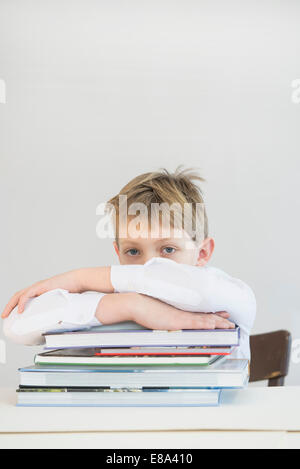 Frustrati ragazzo con pila di libri, close up Foto Stock