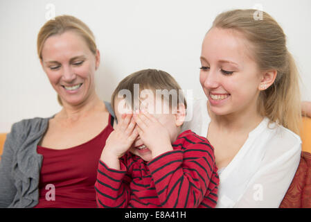 Madre con sua figlia mentre il figlio che copre gli occhi sorridenti Foto Stock