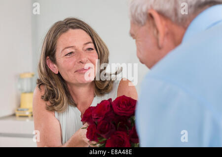 Senior uomo dando rose rosse per donna Foto Stock