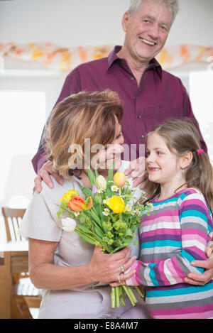 La nipote bouquet di handover alla nonna e nonno in background Foto Stock