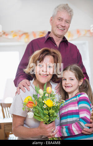 La nipote bouquet di handover alla nonna e nonno in background Foto Stock
