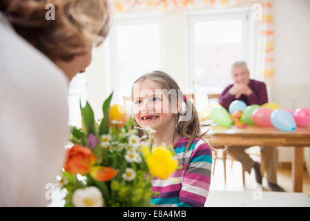 La nipote bouquet di handover alla nonna e nonno in background Foto Stock