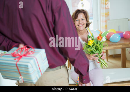 Senior man mano sul presente alla donna il compleanno, sorridente Foto Stock