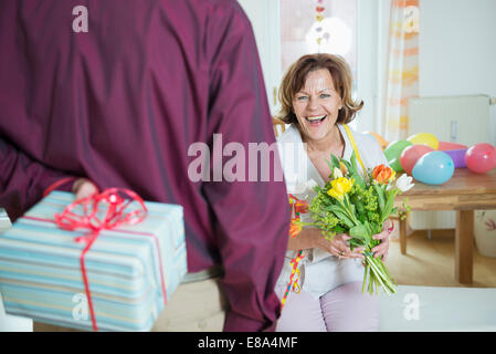 Senior man mano sul presente alla donna il compleanno, sorridente Foto Stock