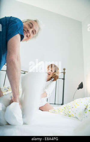 Paio di lotta di cuscini sul letto, sorridente Foto Stock