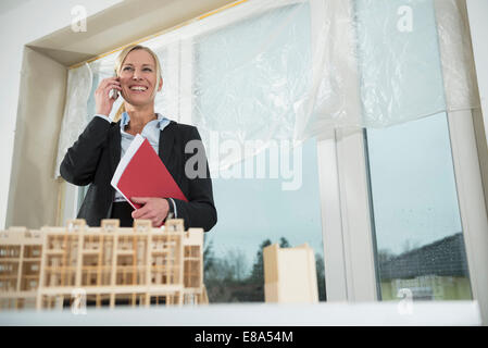 Architetto femmina telefonando al sito di costruzione del nuovo edificio Foto Stock