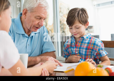 I bambini a fare i compiti di scuola con il loro nonno Foto Stock