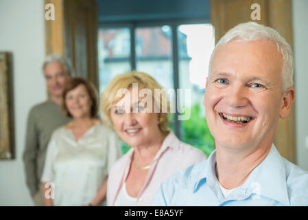 Ritratto di uomo con i suoi amici nel salotto, sorridente Foto Stock