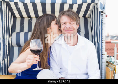 Giovane aventi vite in coperta spiaggia di vimini sedia, sorridente Foto Stock