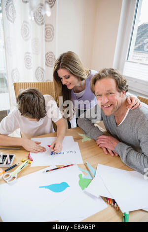 Ragazzo il disegno di una foto con i genitori a tavola Foto Stock