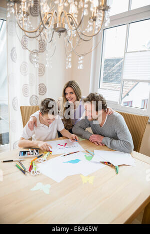 Ragazzo il disegno di una foto con i genitori a tavola Foto Stock