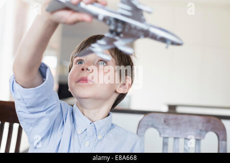 Ragazzo giocando con aeroplano giocattolo, sorridente Foto Stock