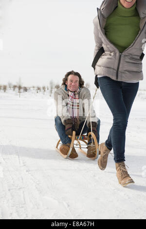 Donna Uomo di trascinamento sulla slitta nella neve, Baviera, Germania Foto Stock