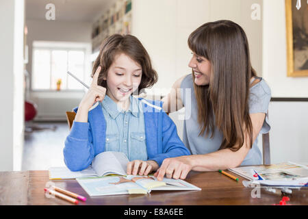 Madre aiutare la figlia in compiti, sorridente Foto Stock