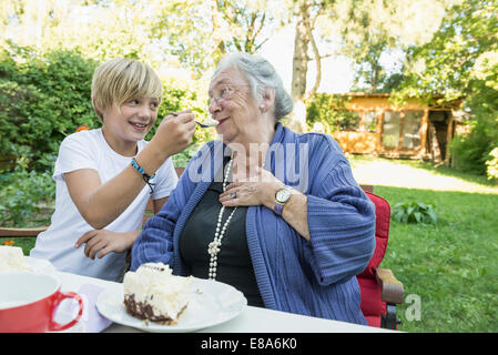 Nipote alimentando la sua nonna con la torta di panna Foto Stock