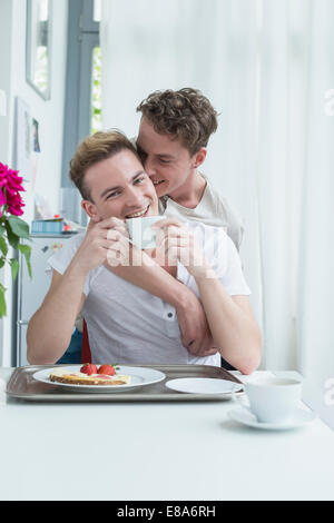 Coppia omosessuale avente colazione insieme sorridente Foto Stock