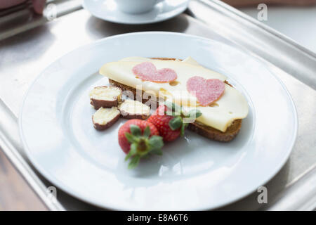 Pane con formaggio, fragola e a forma di cuore ad salame sulla piastra, close up Foto Stock