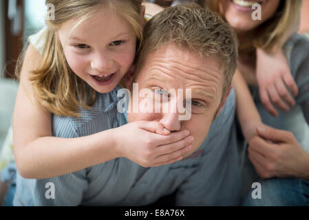 Figlia di padre che copre la bocca con la mano Foto Stock