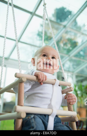 Ritratto di sorridere bimbo seduto in uno swing Foto Stock