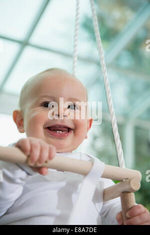 Ritratto di ridere bimbo seduto in uno swing Foto Stock