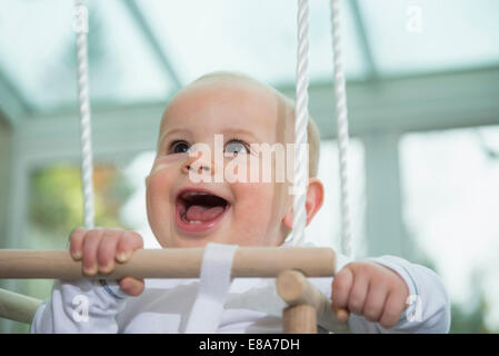 Ritratto di ridere bimbo seduto in uno swing Foto Stock