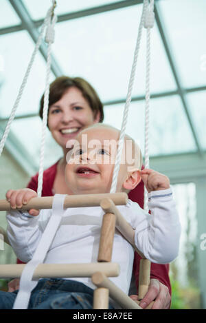 Happy bimbo seduto in uno swing Foto Stock