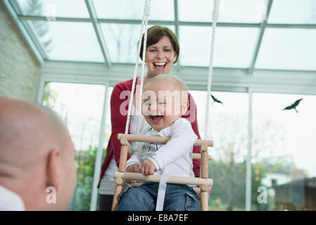 Happy bimbo seduto in uno swing Foto Stock