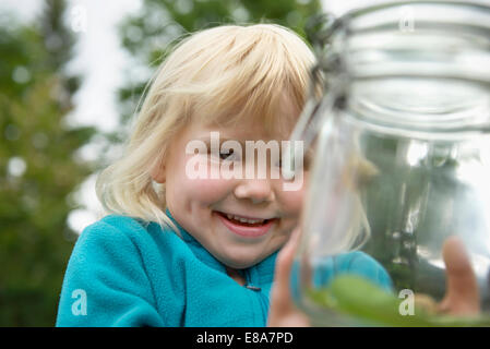 Piccola ragazza bionda raccoglieva lumache in jam-jar Foto Stock