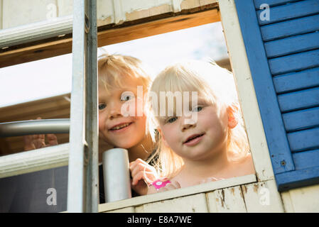 Piccolo Ragazzo e ragazza guardando fuori di casa ad albero Foto Stock