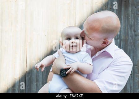 Padre baciare azienda baby figlio orgoglioso sorridente Foto Stock