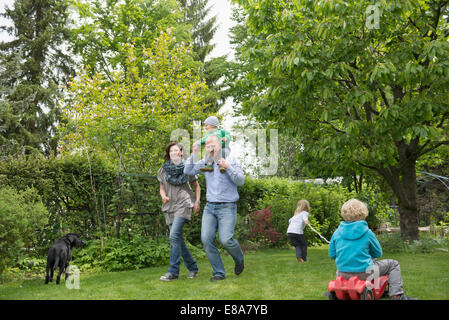 I genitori a giocare in giardino con tre bambini piccoli Foto Stock