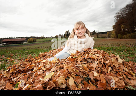 Felice ragazza nel mucchio di foglie di autunno Foto Stock