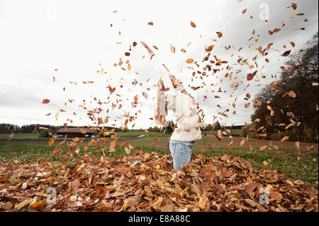 Felice ragazza gettando le foglie di autunno Foto Stock