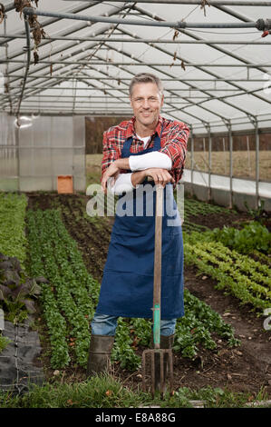 Uomo con forcone in serra Foto Stock