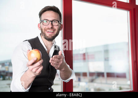 uomo d'affari che offre un sorriso alla mela Foto Stock