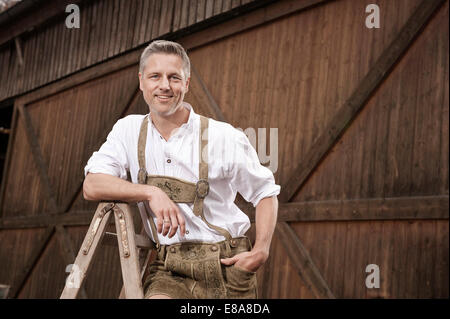 Uomo in lederhosen sulla fattoria, Barvaria, Germania Foto Stock