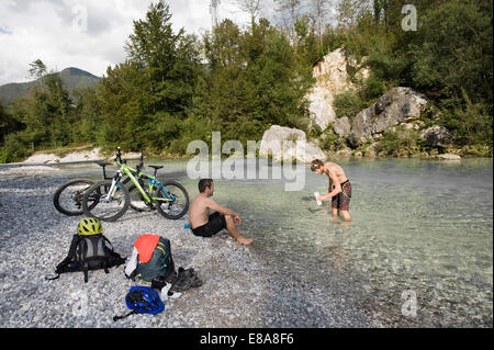 Due mountain bikers avente un riposo a Soca river, Tolmin, Istria, Slovenia Foto Stock