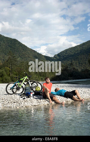 Due mountain bikers avente un riposo a Soca river, Tolmin, Istria, Slovenia Foto Stock