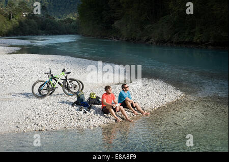 Due mountain bikers avente un riposo a Soca river, Tolmin, Istria, Slovenia Foto Stock